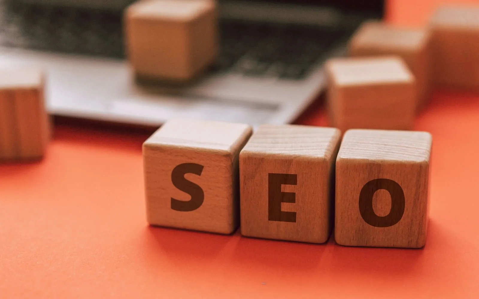 Wooden blocks spelling SEO on a laptop keyboard convey digital marketing concepts.
