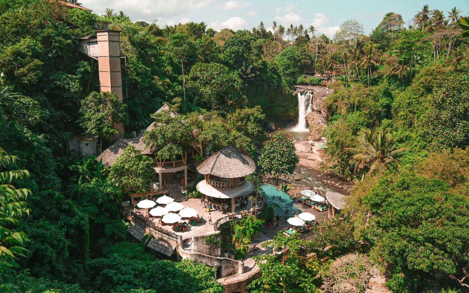A serene tropical resort nestled in a lush forest in Ubud, Bali, featuring a stunning waterfall.