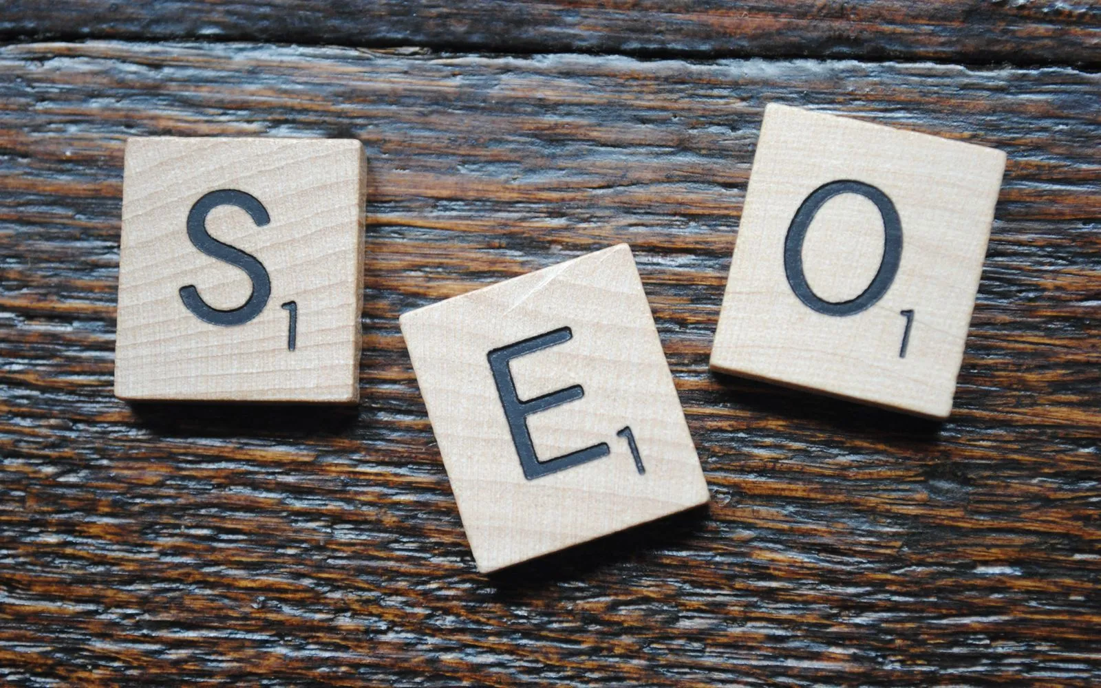 Close-up of Scrabble tiles spelling SEO on a wooden table for content strategy.