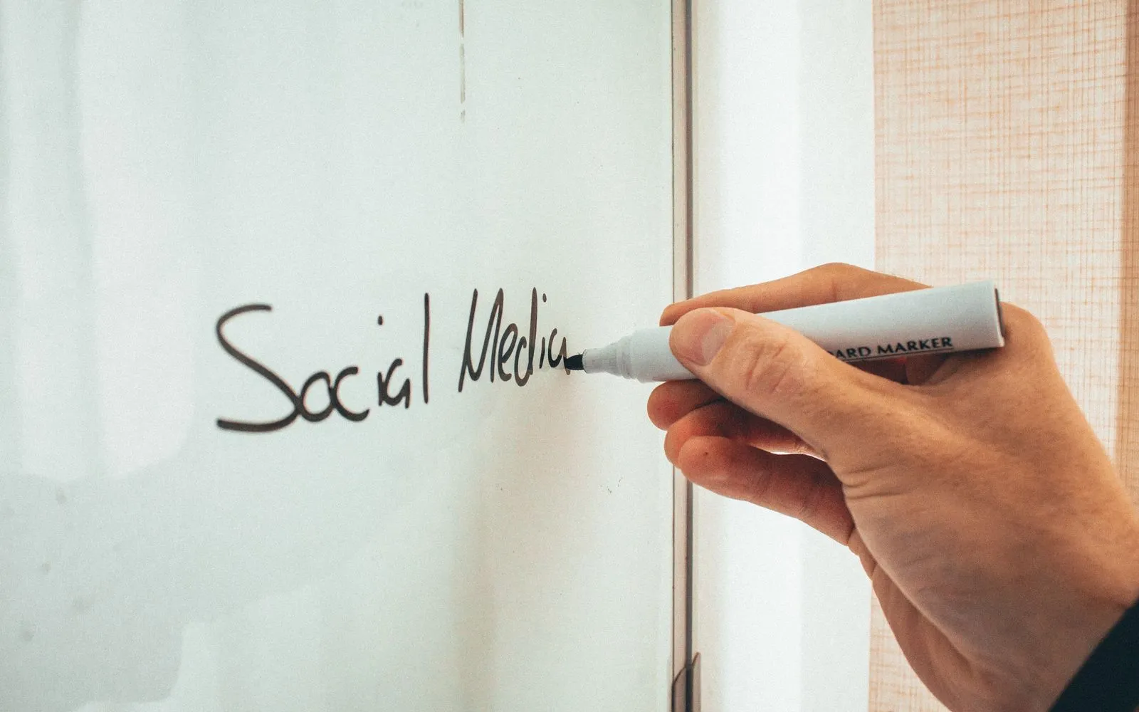 Crop anonymous male teacher writing on whiteboard with marker during social media training courses