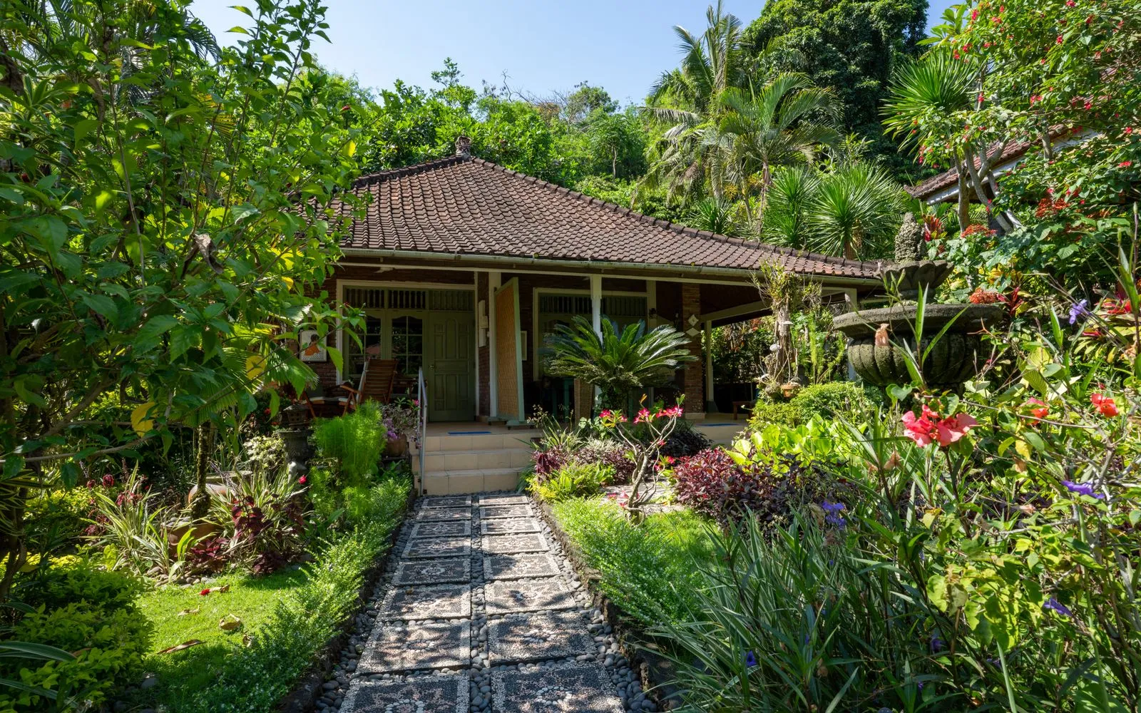 Explore a serene, lush Balinese garden villa surrounded by vibrant tropical foliage.