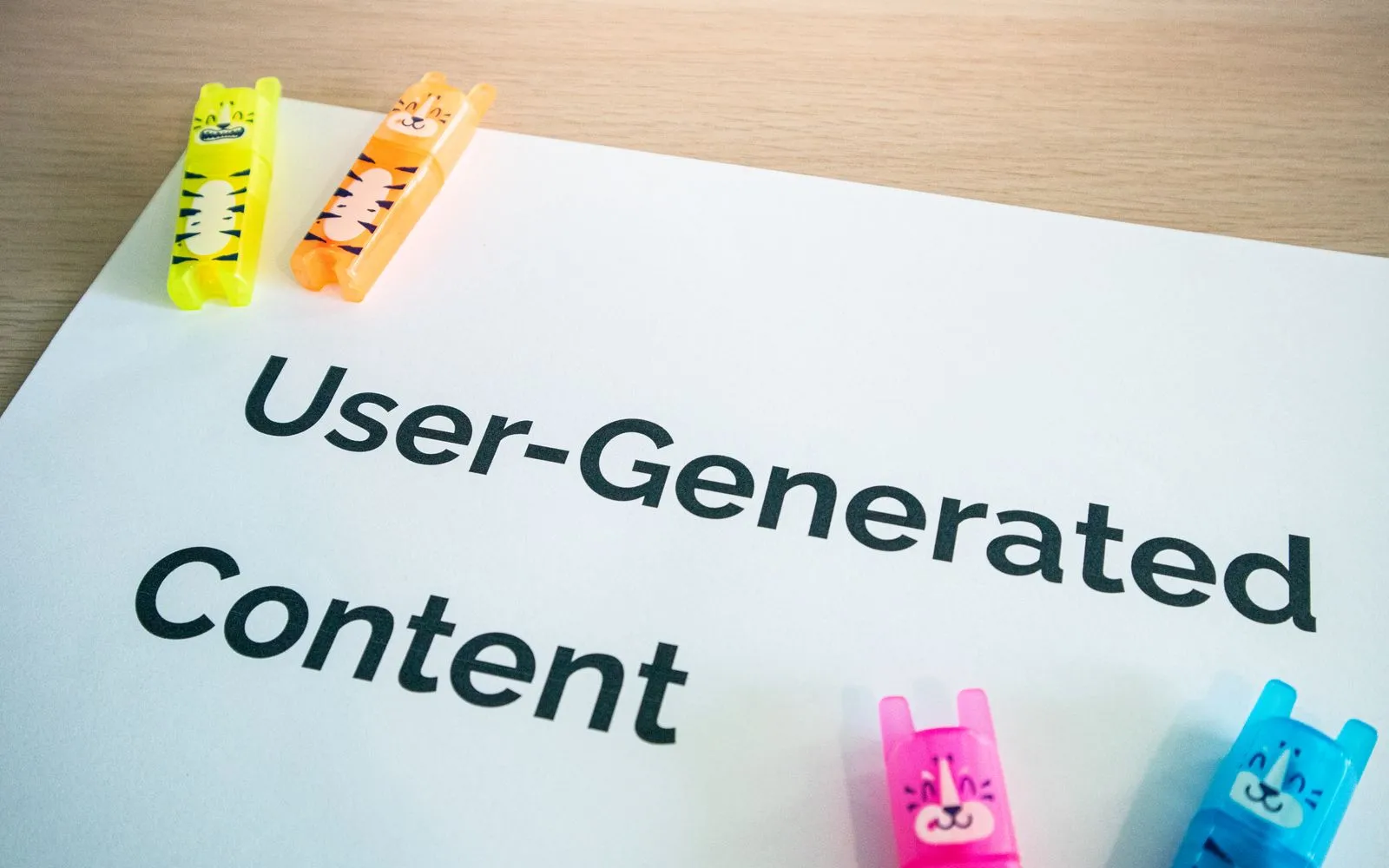 Bright highlighters on a 'User-Generated Content' note against a wooden desk.