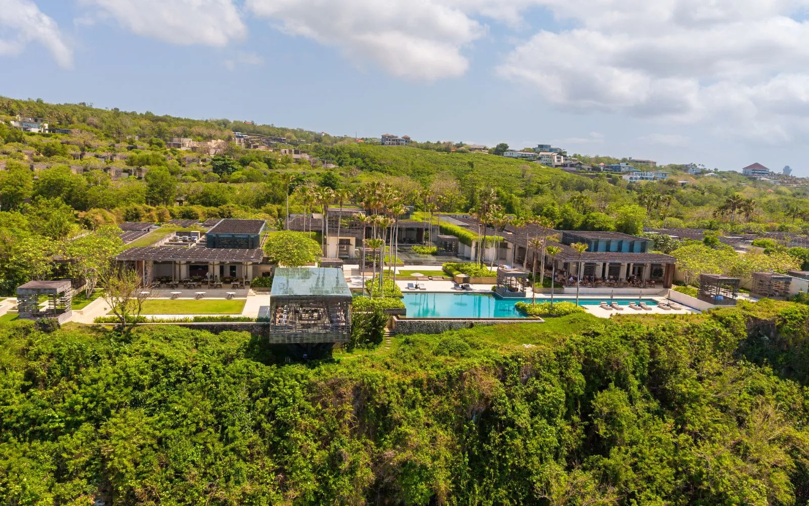 Aerial view of a luxurious villa with an infinity pool on a cliffside in Bali, Indonesia.